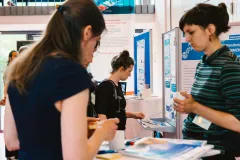 Drei Teilnehmerinnen im Gespräch am Informationsstand des Monitoringzentrums auf dem 2. Forum.