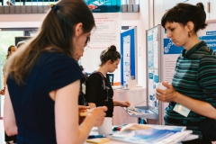 Drei Teilnehmerinnen im Gespräch am Informationsstand des Monitoringzentrums auf dem 2. Forum.