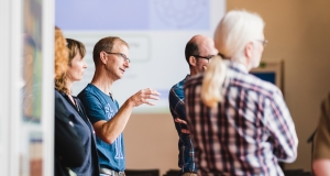 Teilnehmende stehen und diskutieren beim World Café