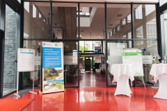 Entrance area of the conference venue with information material, roll-up and bar tables