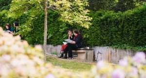 Two people talk on the sidelines of the event in the outdoor green area. 