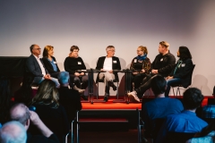 Participants of the panel discussion sitting in a semicircle on the stage.