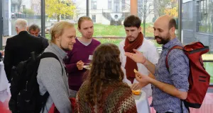 Four men and one woman standing around a table, engaging in conversation.