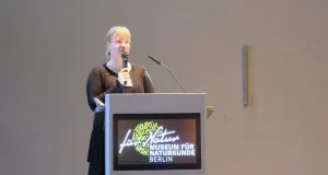 Eine Frau steht hintern einem Pult und hält einen Vortrag