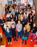 Eine große Gruppen von Menschen steht im Foyer blickt nach oben