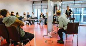 Teilnehmende sitzen in einem Workshopraum im Halbkreis und diskutieren gemeinsam hinter zwei Stellwänden. Auf den Tafeln sind Notizen zu sehen – im Fokus steht der Austausch zum Mehrwert des Biodiversitätsportals für Behörden. 