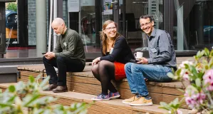 Drei Personen sitzen auf Holzstufen auf einer Terasse