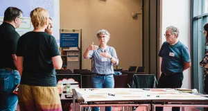 Teilnehmende diskutieren und gestalten ein Plakat.