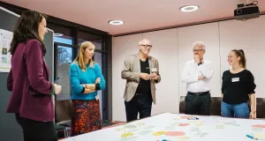 Drei Frauen und zwei Männer stehen an einem Tisch auf dem zahlreiche beschriebene Kärtchen liegen