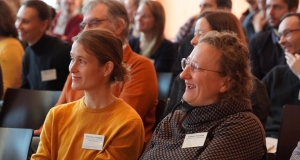 Zwei Frauen sitzen im Publikum und blicken nach vorne Richtung Bühne