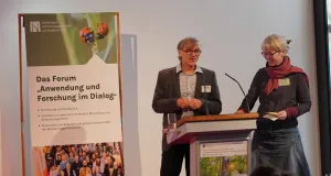 Ein Mann und eine Frau stehen an einem Pult 