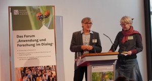 Ein Mann und eine Frau stehen an einem Pult 