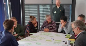 Eine Gruppe von Menschen sitz um einen Tisch und diskutiert