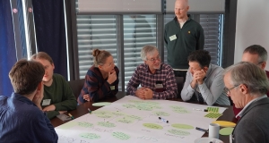 Eine Gruppe von Menschen sitz um einen Tisch und diskutiert