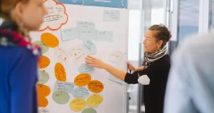 Workshop situation with a colleague who summarises the results using notes on a moderation wall.