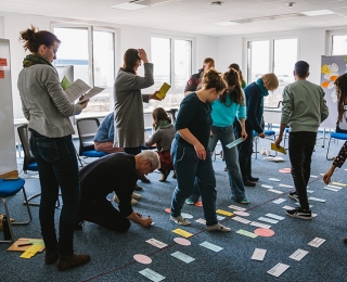 Group photo of the staff from the head office of the National Monitoring Centre for Biodiversity during a retreat in a seminar room. Participants are standing and sitting in a seminar room equipped with moderation boards and work materials. The relaxed atmosphere reflects team spirit and collaboration.