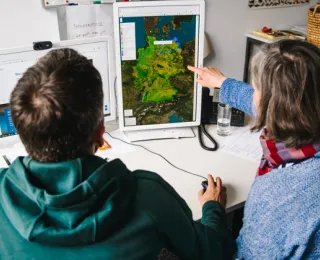 Zwei Personen betrachten gemeinsam am Bildschirm eine Karte Deutschlands mit geografischen Daten.