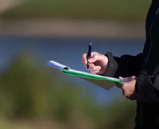 Person notiert in Landschaft etwas auf einen Zettel