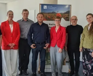Gruppenfoto zeigt acht Personen, die Gäste aus der Ukraine gemeinsam mit den Gastgeber:innen vom Monitoringzentrum 